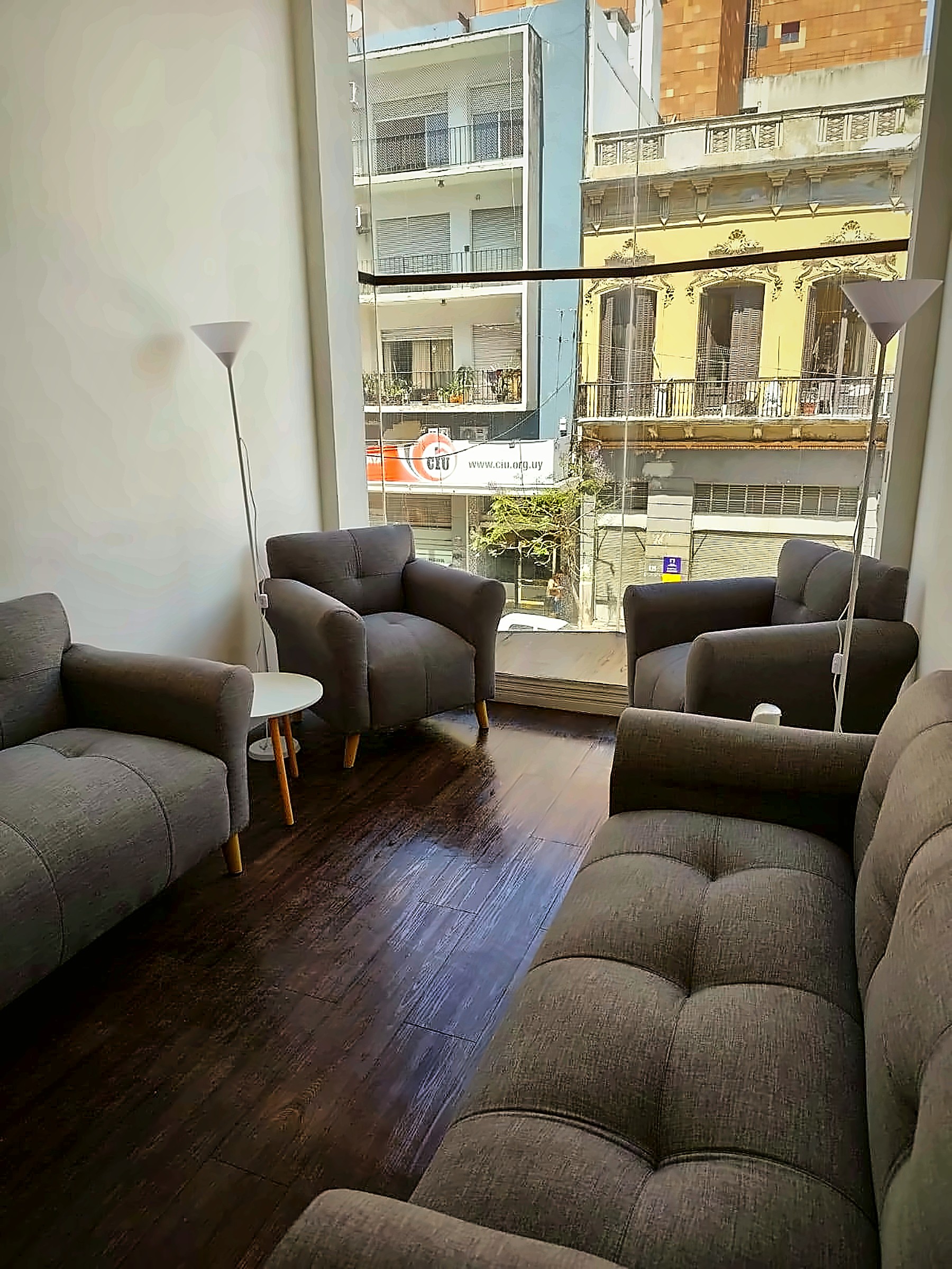 Living de Centro Smart 1 con sillones grises, lámparas de pie y gran ventanal
